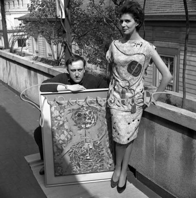 Enrico Baj con una indossatrice. Sfilata dei modelli disegnati dagli artisti per l'Atelier di Bruna Bini e Giuseppe Telese. Milano, marzo 1961
